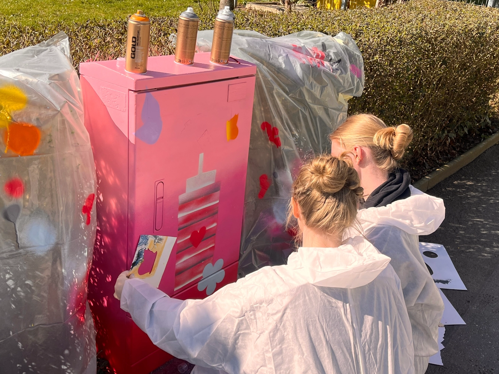 Schülerinnen verschönern einen Stromkasten.