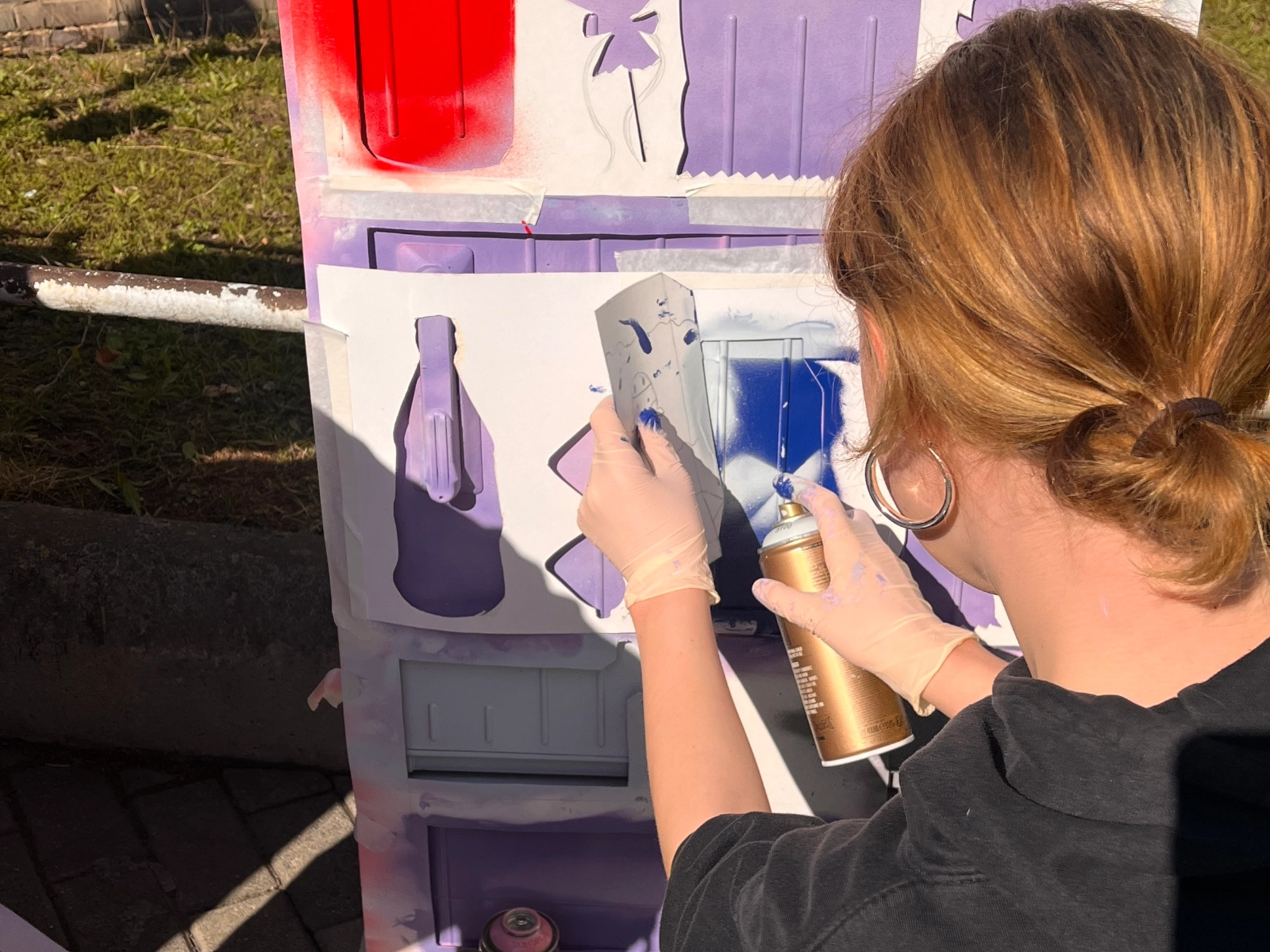 Eine Schülerin verschönert einen Stromkasten mit Graffiti. 