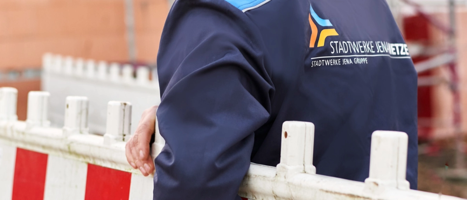 Ein Mitarbeiter der Stadtwerke Jena Netze trägt eine Absperrung